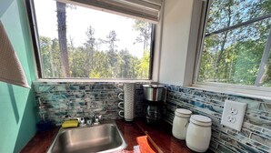 A kitchen with a stainless steel sink, a coffee maker, and storage jars. - Treehouse with golf cart in Shepherd - near Lake with wild alligators (Shepherd)