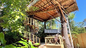 A wooden treehouse with a wooden deck and stairs, surrounded by trees and greenery. - Treehouse with golf cart in Shepherd - near Lake with wild alligators (Shepherd)