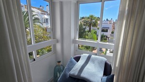 Une pièce donnant sur un quartier résidentiel, une fenêtre à cadre blanc et une petite bouteille décorative posée sur le rebord de la fenêtre.