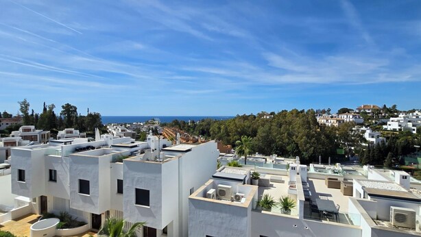 Un quartier résidentiel moderne avec des bâtiments blancs, des toits plats et un ciel d’un bleu éclatant.