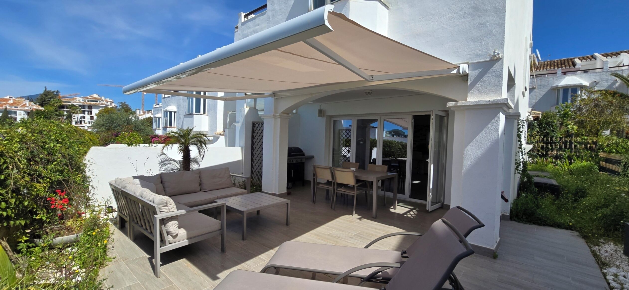 Un patio al aire libre con un sofá, sillas y una mesa.