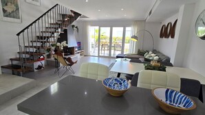 Un salon moderne doté d’un escalier, d’un coin repas et d’une grande fenêtre donnant sur l’extérieur.