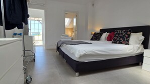 Une chambre à coucher moderne avec un grand lit, une table de chevet, une armoire et un chariot.