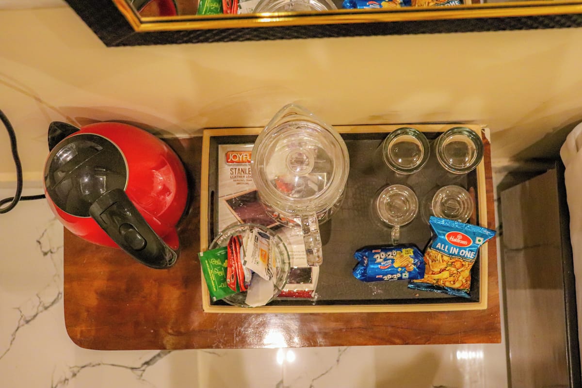 Eine Küchenarbeitsplatte mit einem roten Wasserkocher, einem Glasbehälter und verschiedenen Lebensmitteln, darunter Snacks und Würzmittel.