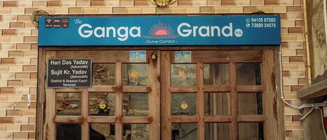 A hotel entrance with a sign reading "The Ganga Grand" and contact information.