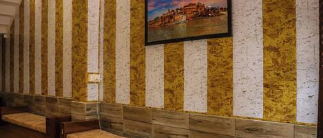 Un vestíbulo de hotel con paredes a rayas, un banco de madera y un cuadro enmarcado con una vista urbana.