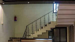 Una escalera con barandilla de madera y pasamanos metálicos que conduce a un piso superior.
