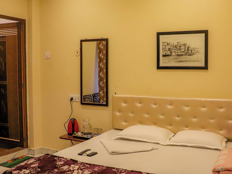 Una habitación de hotel con cama, mesita de noche, espejo y un cuadro en la pared.