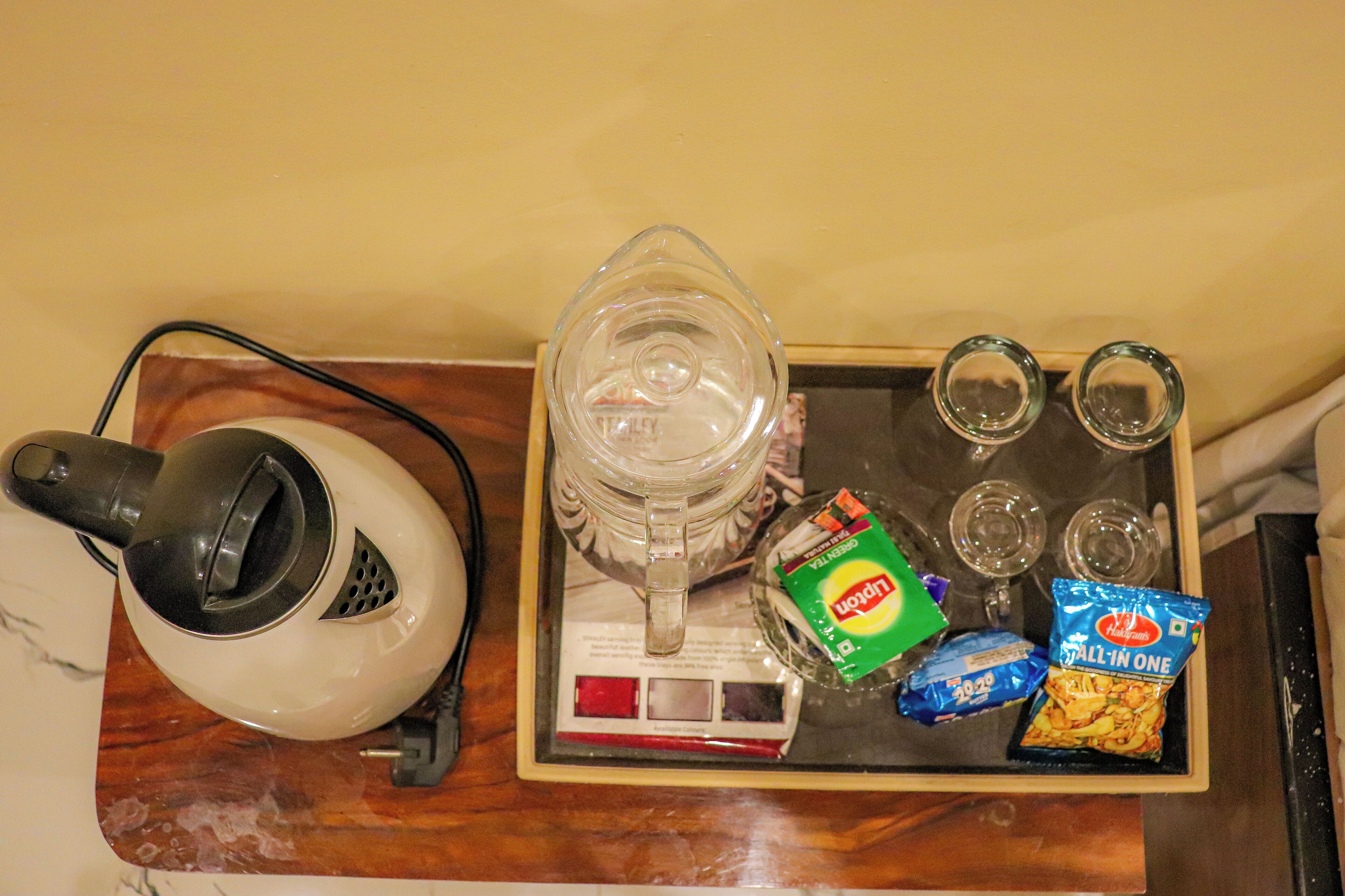 A tray with a kettle, a pitcher, glasses, and snacks.