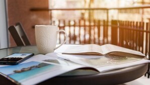 A table with a white pitcher, an open magazine, and a smartphone on a glass table. - Mar25 #11 - Entire Apt, Fully Equipped, 1Bedroom. (Athina)