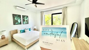A hotel room with a bed, a ceiling fan, a window with curtains, and a framed sign on the wall. - GardenSuite at Aqualara Villa w/ shared Rooftop Infinity Lounge Pool & Patio (Providenciales)