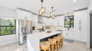 A modern kitchen with white cabinets, stainless steel appliances, and a large island with bar stools.