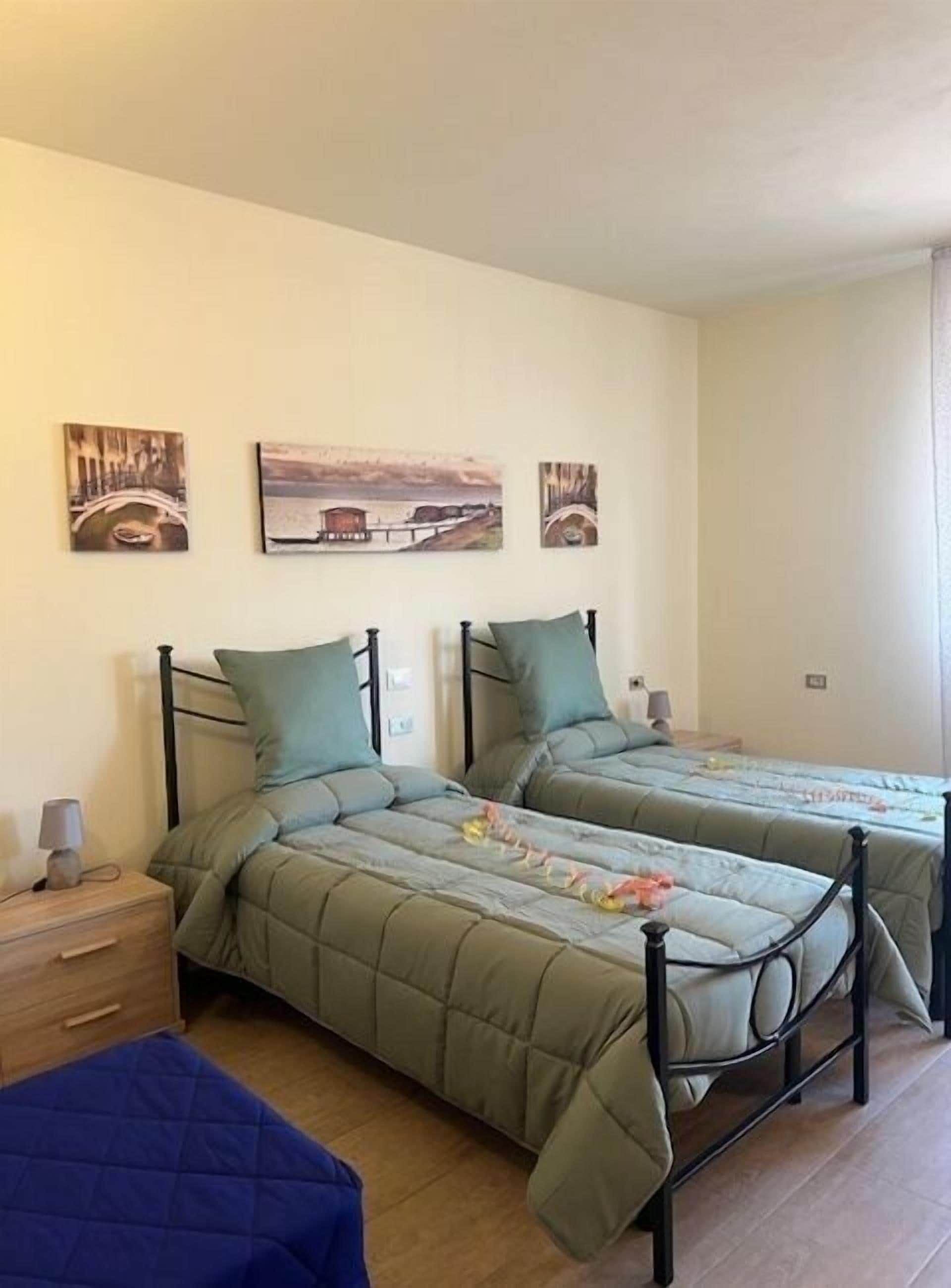 A room with two beds, a nightstand, and wall art.