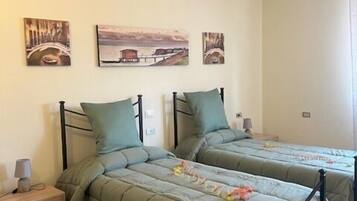 A room with two beds, a nightstand, and wall art.