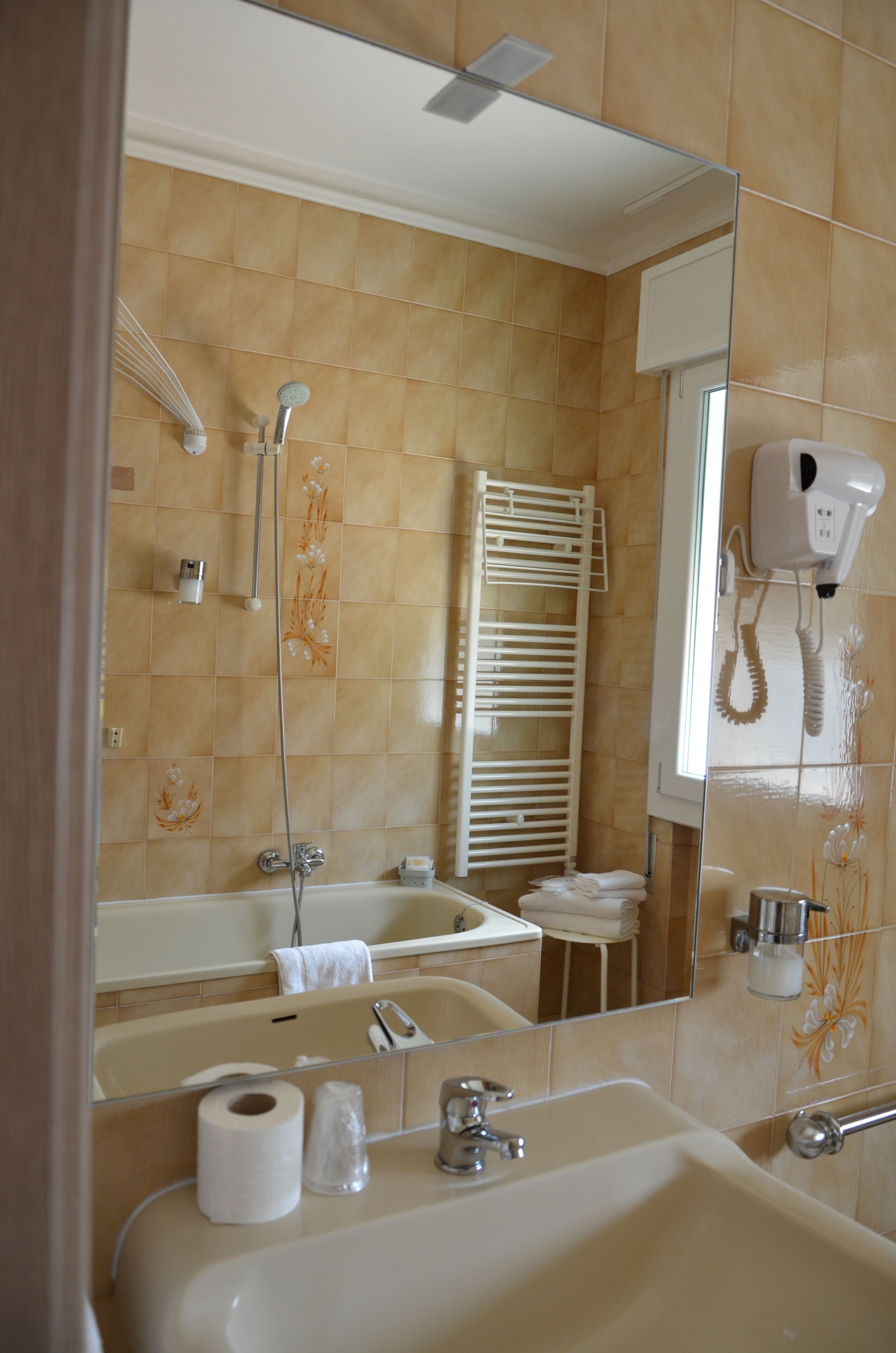 Un baño con bañera, lavamanos, espejo y perchero para toallas.