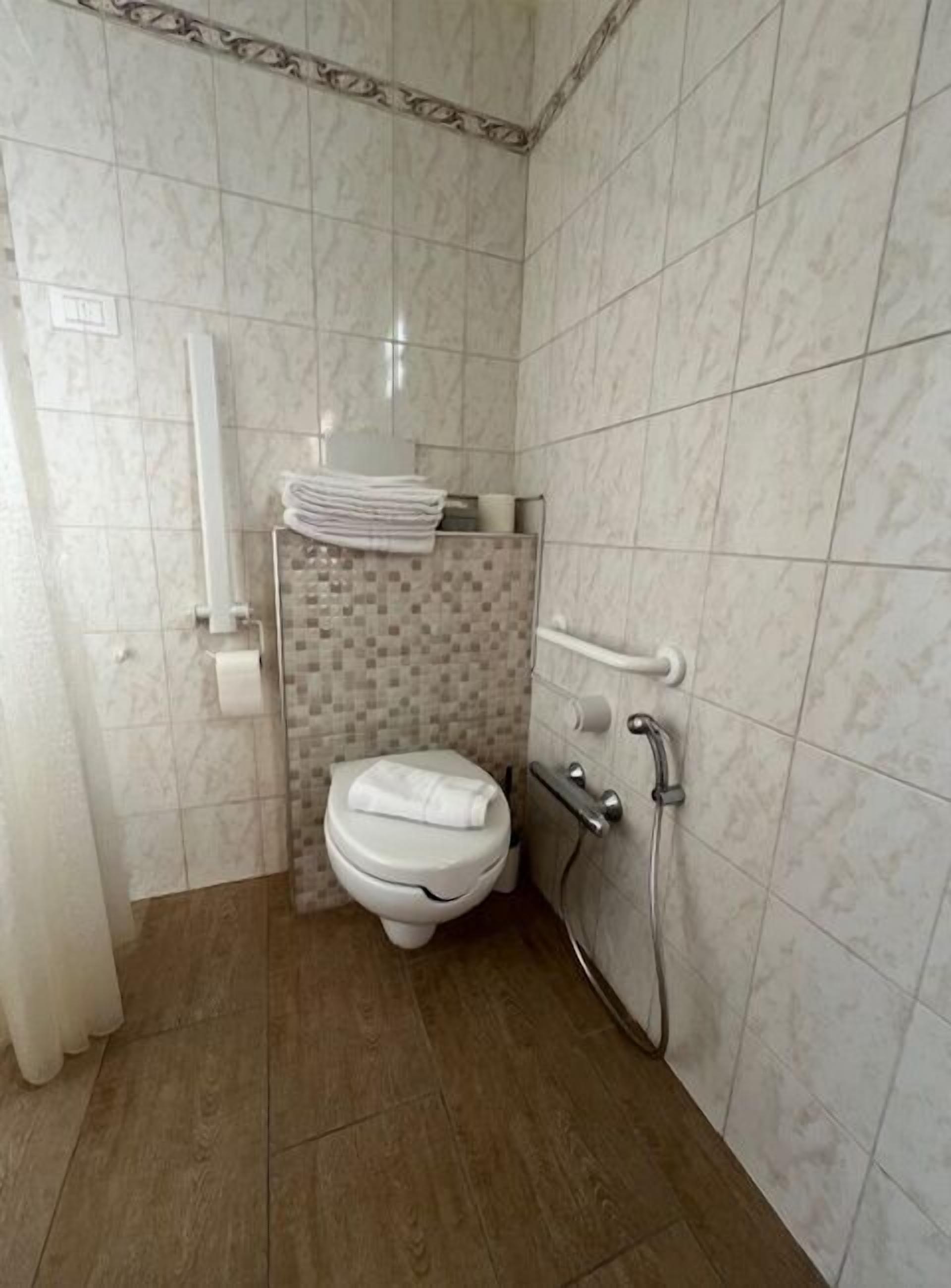 Ein kleines, modernes Badezimmer mit Toilette, Dusche und Handtuchhalter.