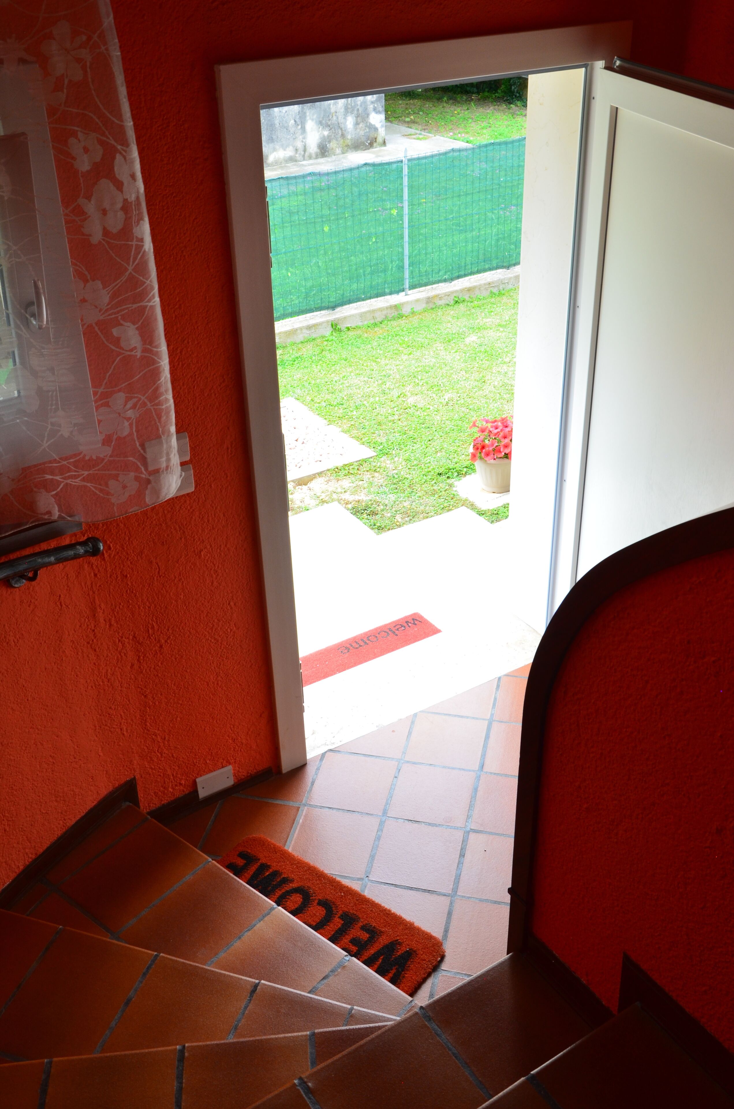 Une pièce aux murs rouges, avec une porte donnant sur une pelouse verte.