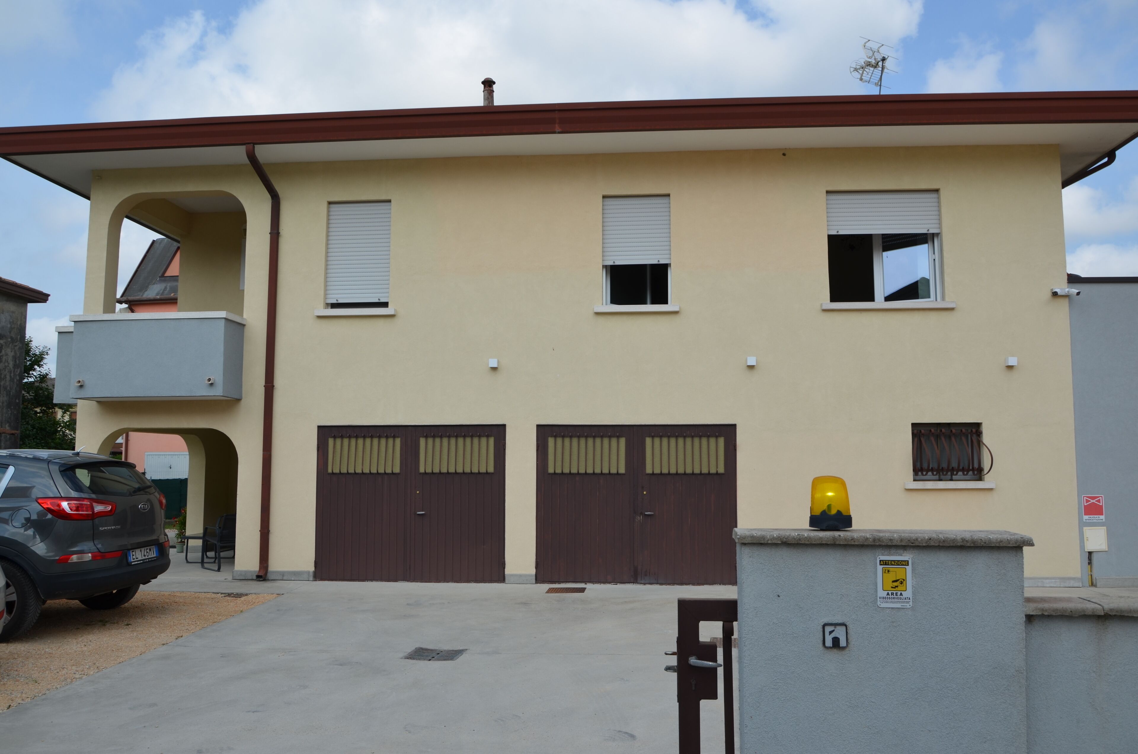 Un bâtiment à deux étages, doté d’une façade beige, de deux portes doubles marron et d’une petite fenêtre sur laquelle repose un objet jaune.