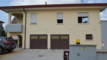 Un bâtiment à deux étages, doté d’une façade beige, de deux portes doubles marron et d’une petite fenêtre sur laquelle repose un objet jaune.