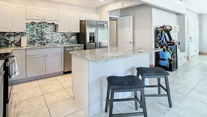 Eine moderne Küche mit weißen Schränken, einem Edelstahl-Kühlschrank, einer Granitarbeitsplatte und einem integrierten Wasserspender.