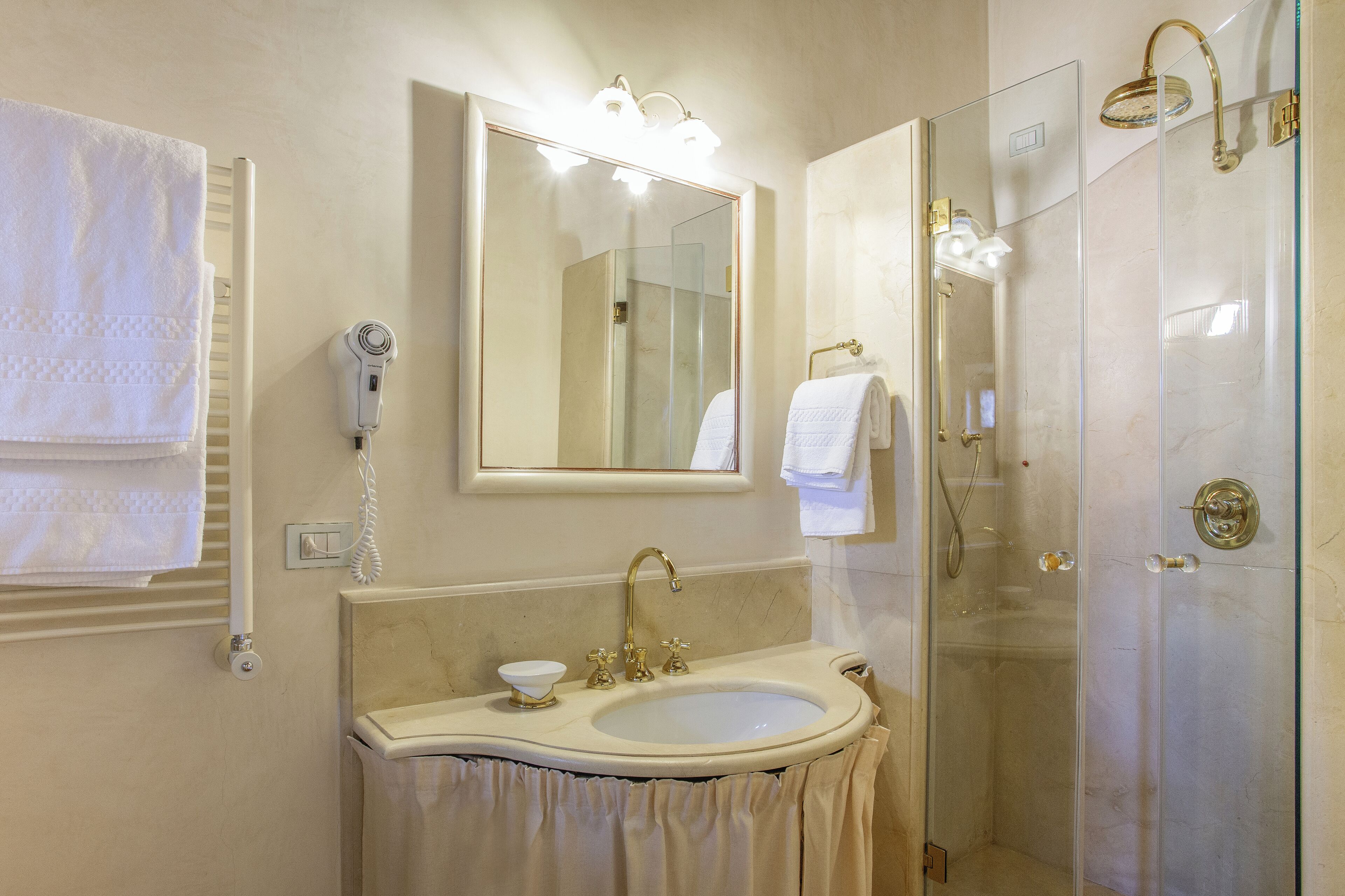 Une salle de bain équipée d’un lavabo, d’un miroir, d’un porte-serviettes et d’une douche.