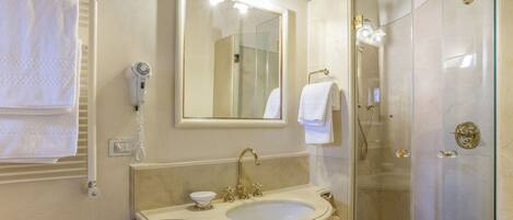 A bathroom with a sink, mirror, towel rack, and shower.