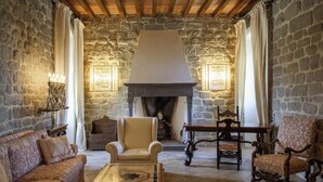 Une pièce chaleureuse avec des murs en pierre, une cheminée, un canapé, un fauteuil et une table.
