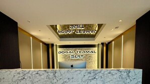 A reception desk with a marble top and a digital screen displaying 'DOGAL TERMINAL SUIT'. - Doğal Termal Suit (Gediz)
