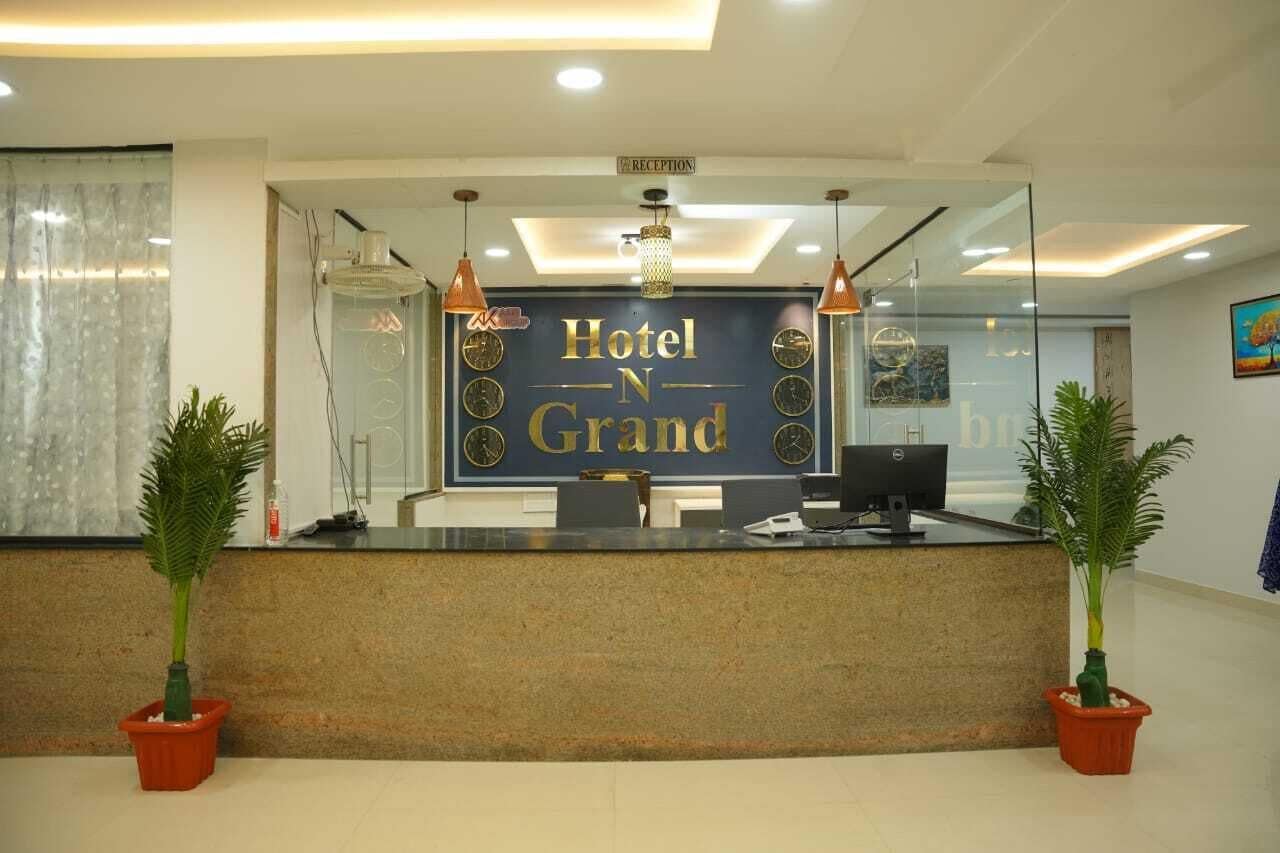 A hotel reception desk with a sign reading "Hotel N Grand" and a reception area with two potted plants.