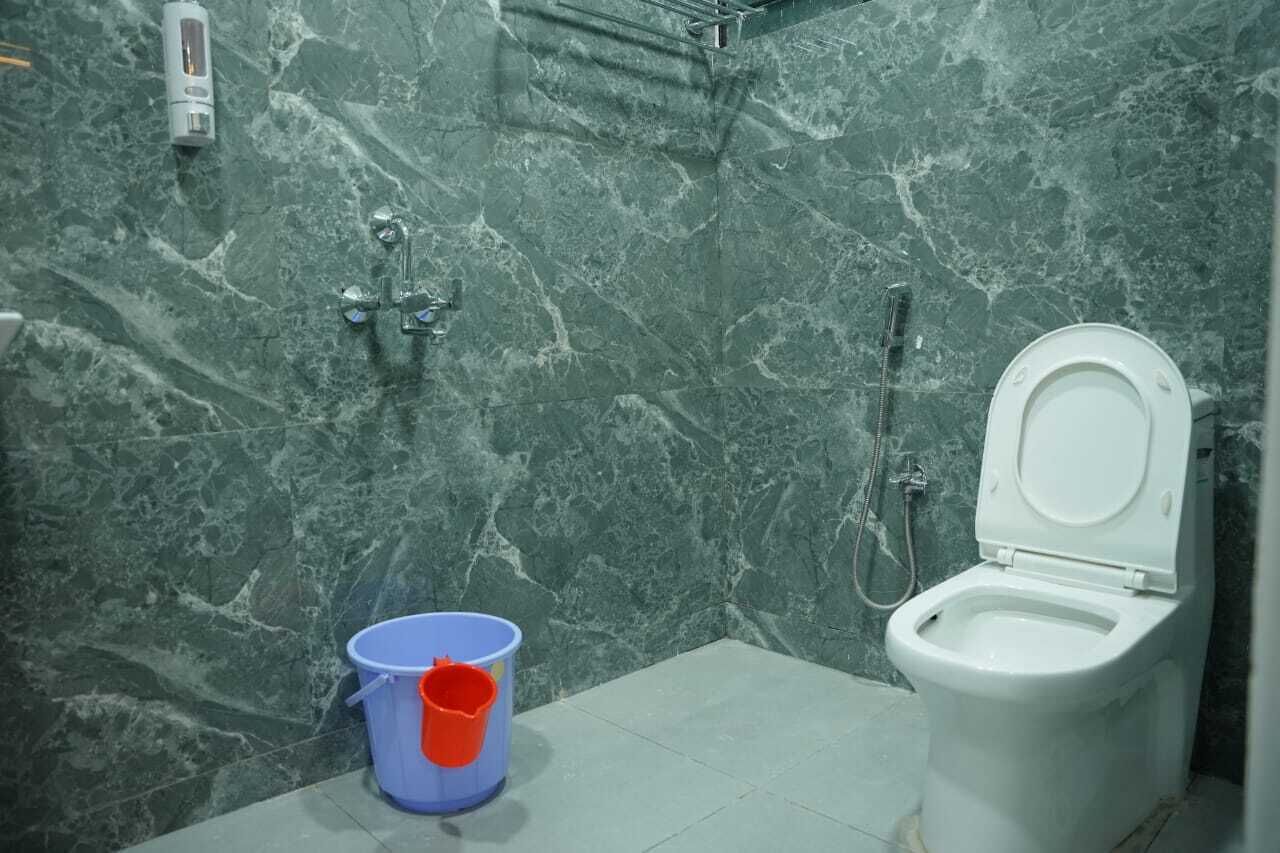 Een badkamer met toilet, douche en een marmeren wand.
