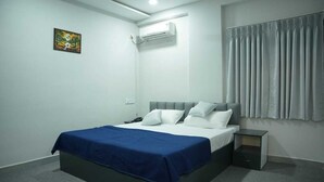 Habitación de hotel moderna con una cama individual, una mesita de noche, aire acondicionado montado en la pared y una ventana con cortinas.