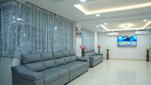Una sala moderna con un sofá gris, jarrones decorativos y un televisor de pantalla plana en la pared.