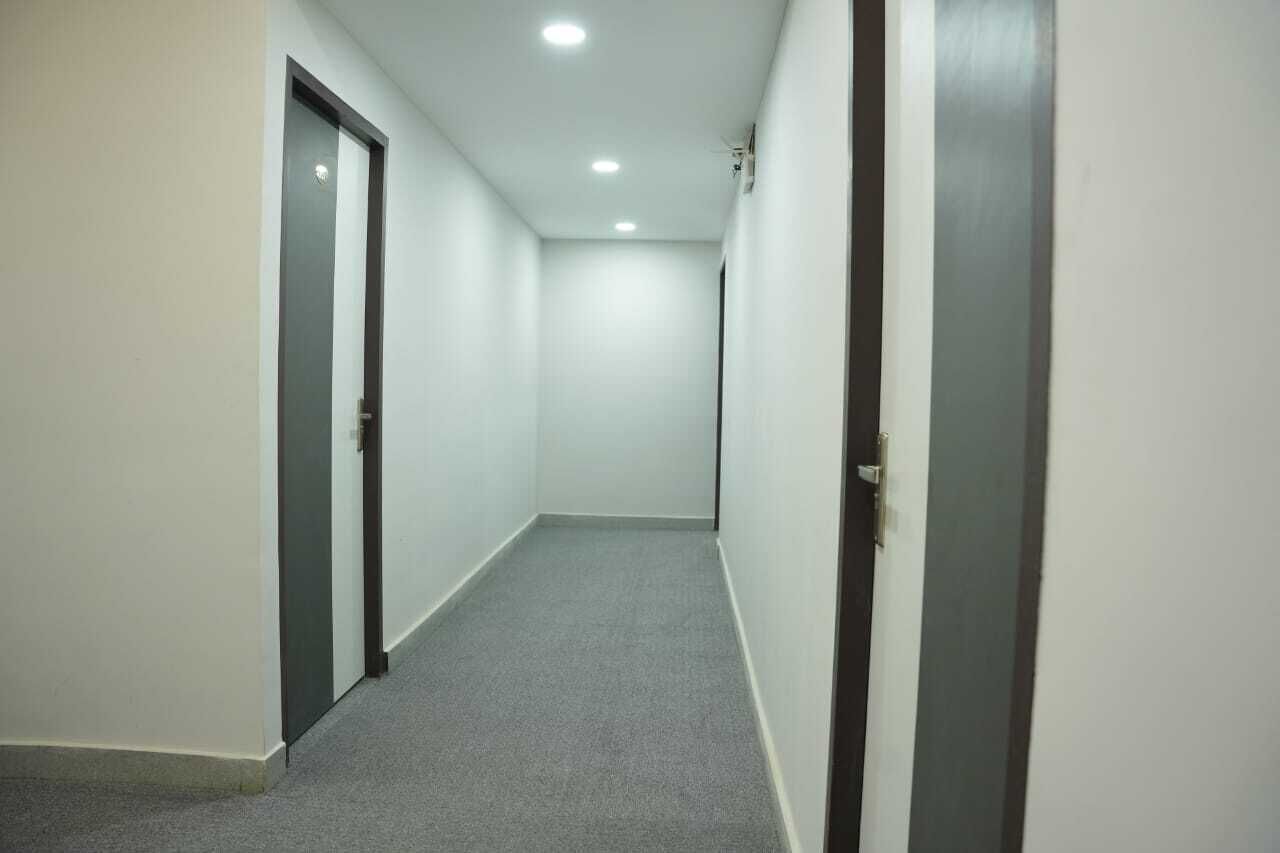 A narrow, well-lit hallway with carpeted floors and white walls.