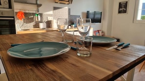 Una mesa de madera con dos platos verdes, dos vasos transparentes y un cuchillo.