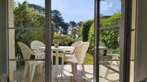 A patio with a round table and four chairs, surrounded by glass doors.
