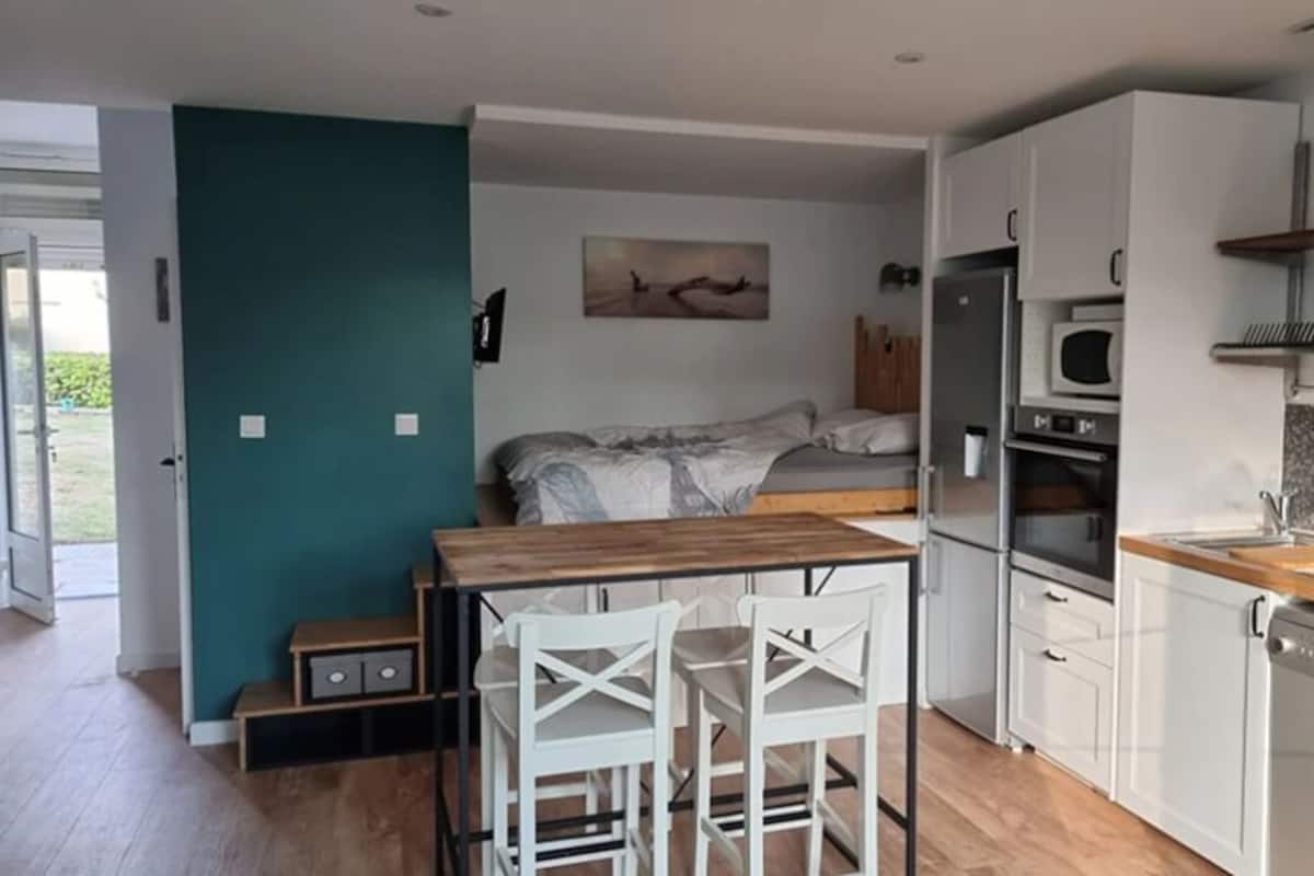 A compact kitchen with a dining area, a bed, and a view of the outdoors.