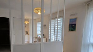 A bedroom with a large bed, two towels, a wardrobe, a hanging light fixture, and a window with blinds.