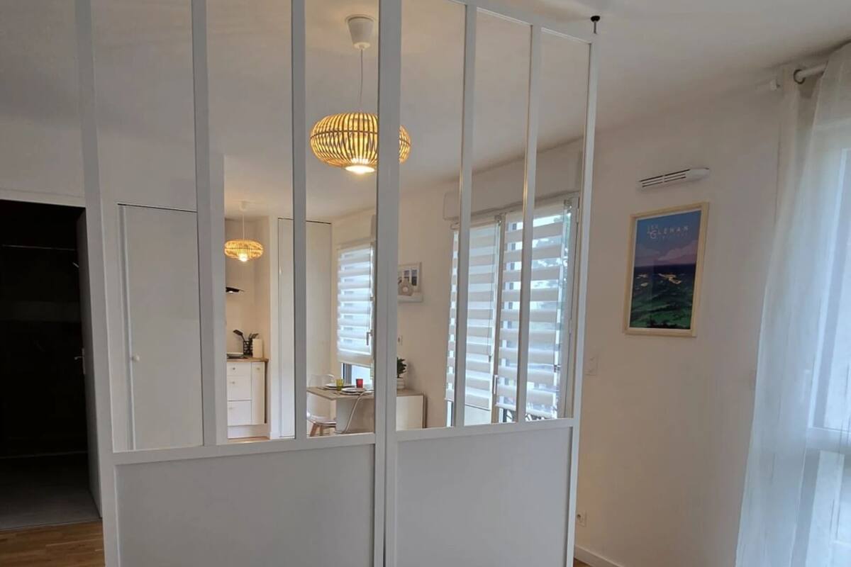 A bedroom with a large bed, two towels, a wardrobe, a hanging light fixture, and a window with blinds.