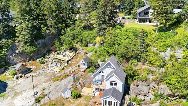 A large house with a balcony, surrounded by dense forest and rocky terrain. - Quarry Village Compound; 4BR + Hot Tub on a workin (Spruce Head)