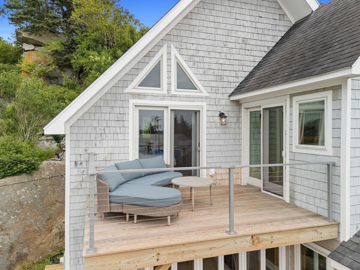 A house with a deck, a wicker sofa, and a small table.