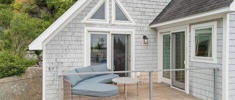 A house with a deck, a wicker sofa, and a small table.