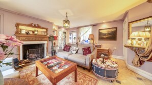 A cozy living room with a fireplace, a sofa, a coffee table, and a decorative cart.