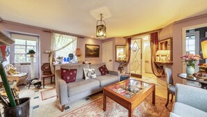 A cozy living room with a sofa, armchairs, a coffee table, and a dining area with a lamp.