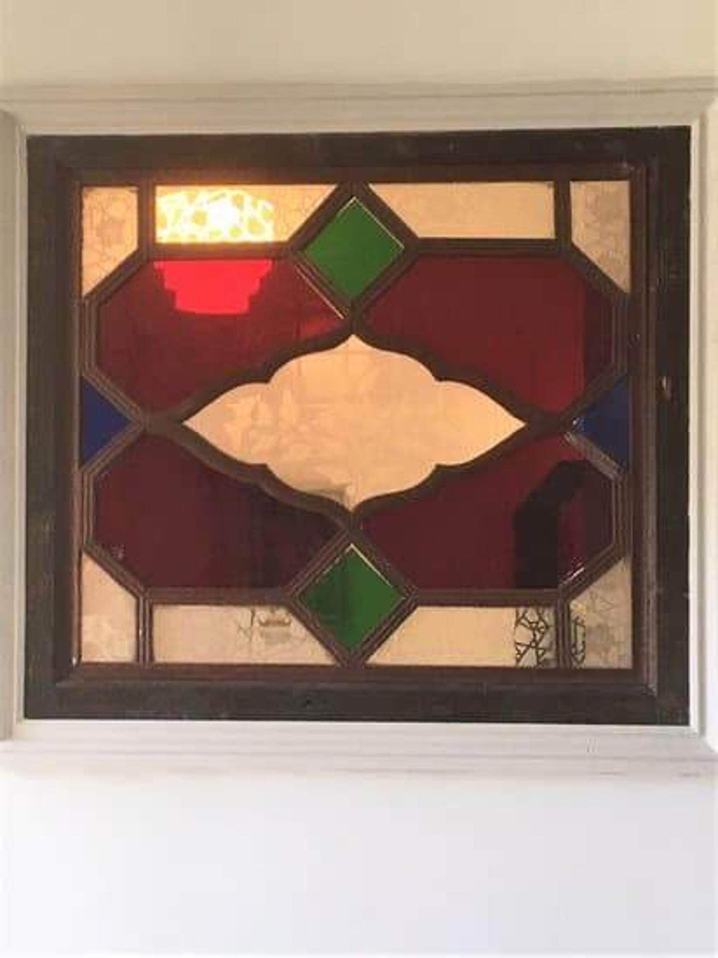 Una ventana de vitral con diseños geométricos y forma de diamante.