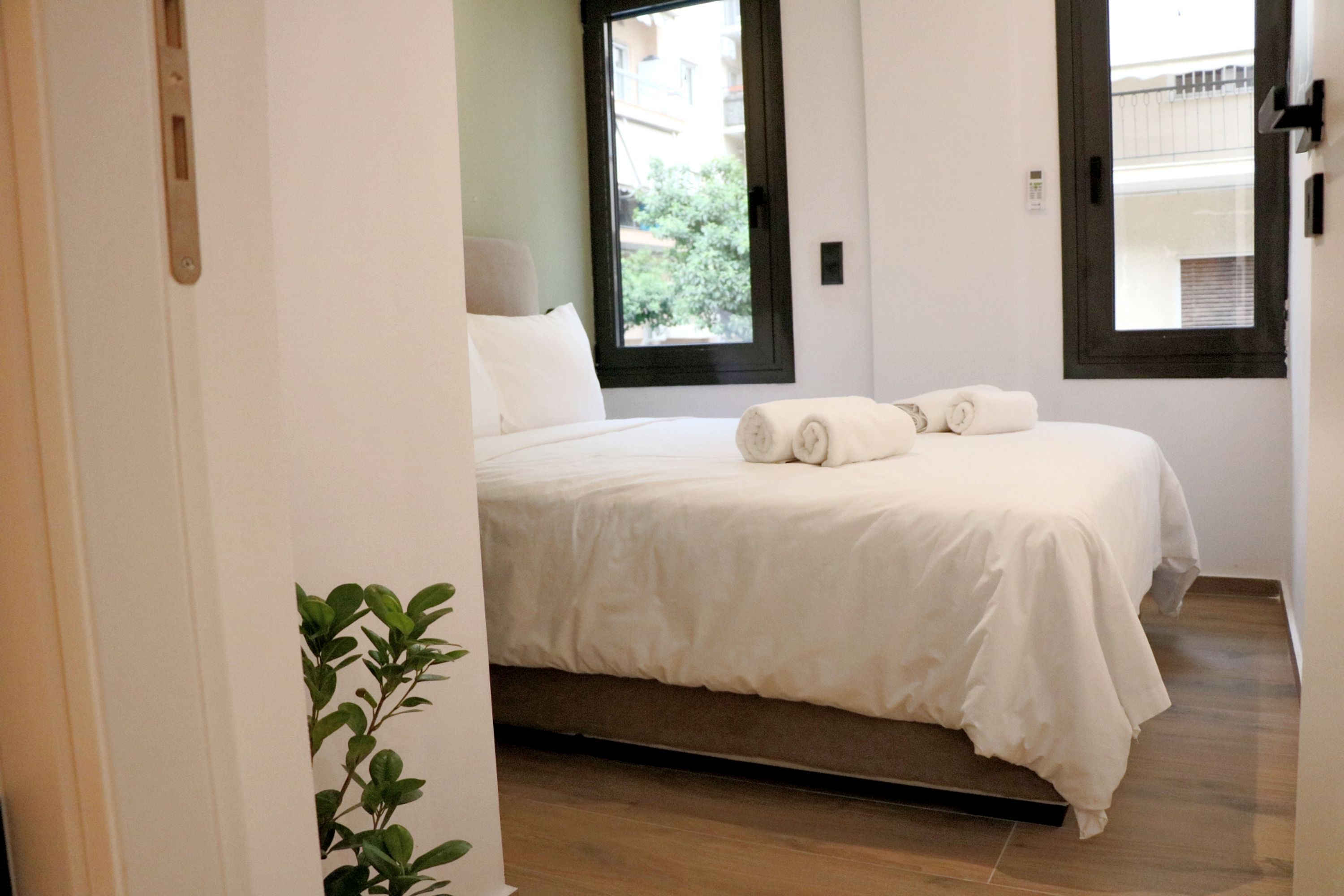 A bedroom with a bed, a window, and a plant.