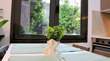 A kitchen with a window, a plant in a vase, and a table with placemats.