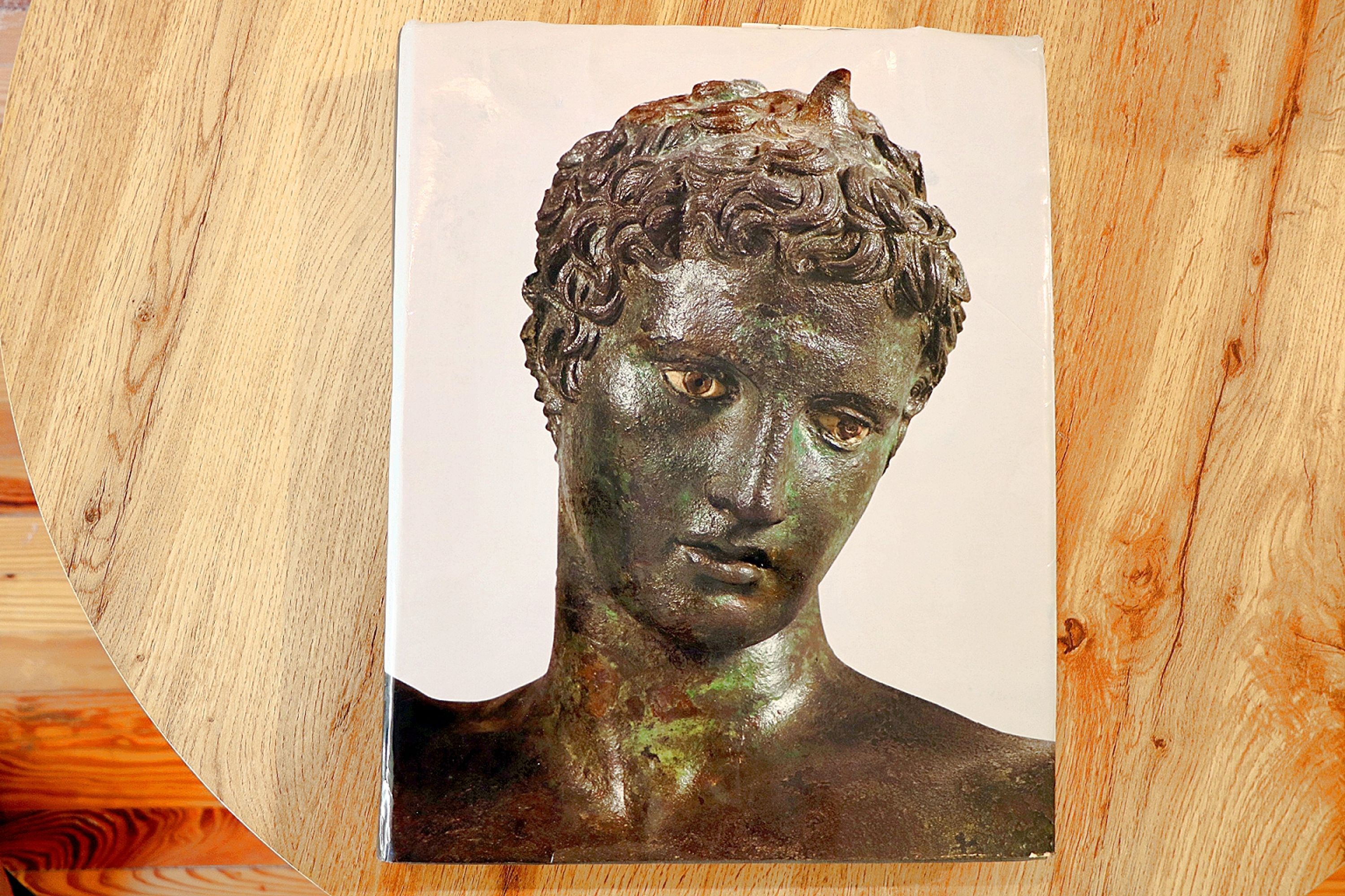 Um busto de bronze sobre uma superfície de madeira.