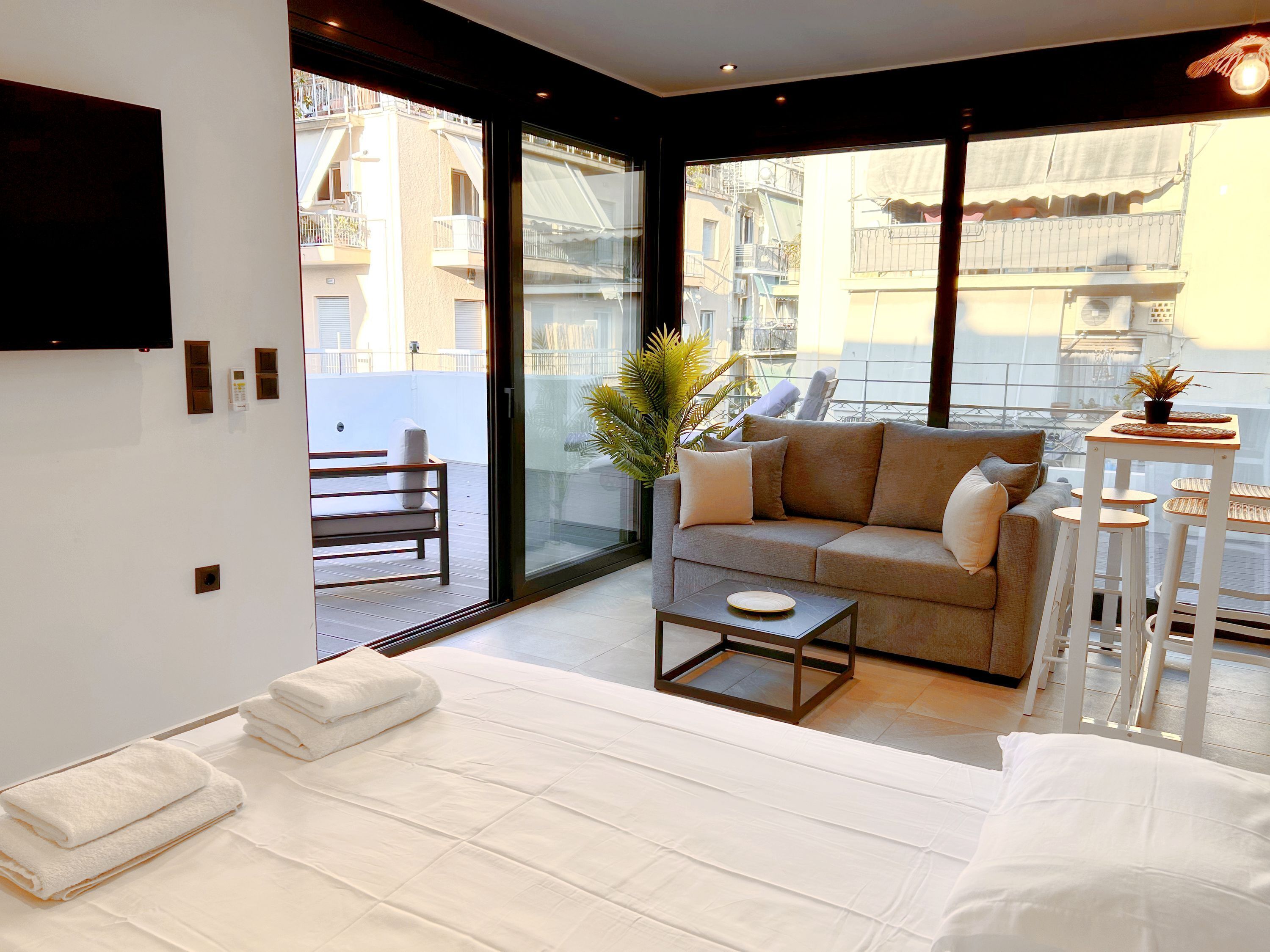 Una sala de estar moderna con sofá, mesa de centro y balcón con vista a edificios.