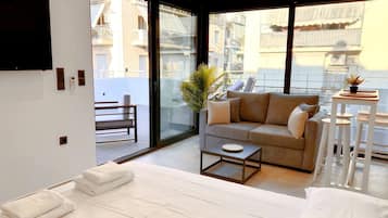 Una sala de estar moderna con sofá, mesa de centro y balcón con vista a edificios.