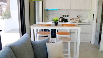 A modern kitchen with white cabinets, a marble backsplash, and a dining area with a sofa and chairs.